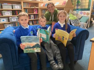 Friends of Ainderby Steeple School Treasurer Nicky Ruddick, with pupils, from left to right, Eddie, Alfred and Billy sitting on a sofa reading books.