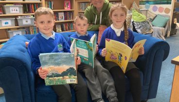 Friends of Ainderby Steeple School Treasurer Nicky Ruddick, with pupils, from left to right, Eddie, Alfred and Billy sitting on a sofa reading books.