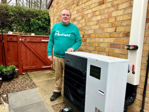 Mr Smith stood outside his home next to the Air-source Heat Pump.