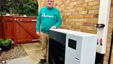 Mr Smith stood outside his home next to the Air-source Heat Pump.