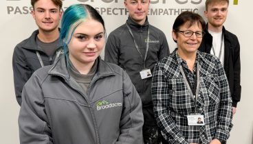 3 men at the back and 2 women at the from in front of wall with Broadacres logo.