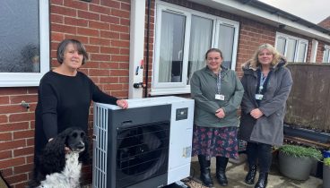 Julie, Polly, Helen and Joanne standing in front of an air-source heat pump